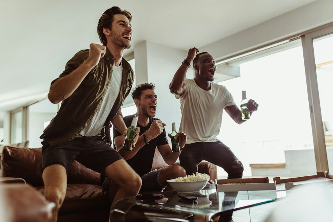 Friends on a couch cheering at a game on television, watching sports with Varesteam4K IPTV